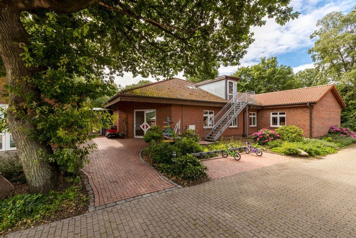 Kirchenkindergarten mit rotem Ziegeldach, umgeben von Bäumen.