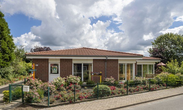 Kirchenkindergarten mit blühenden Rosenbüschen.