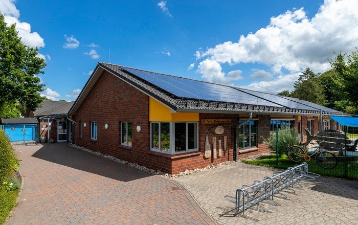 Kindergarten mit Solaranlage, Zufahrt und Kunst im Freien.