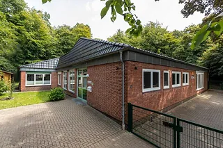 Kirchenkindergarten-Verwaltungsgebäude umgeben von Bäumen.