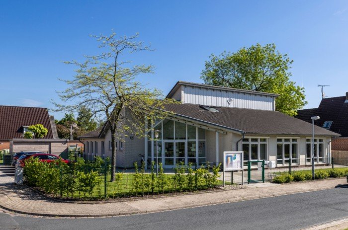 Gemeindezentrum mit hellen Fenstern und Grünfläche.