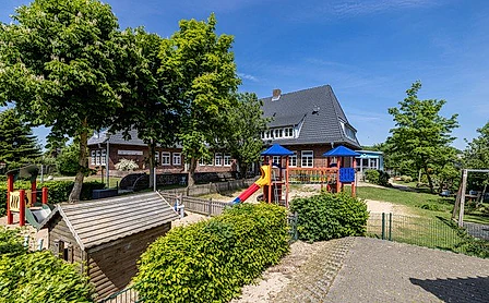 Kirchliche Schule mit Rutschen, Schaukeln und Spielhäusern.